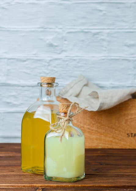 Ensemble de caisse en bois et chiffon blanc et bouteille de jus de citron sur une surface en bois et blanche. vue de côté. espace pour le texte