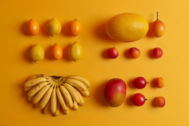 Ensemble de délicieux fruits tropicaux pour la consommation. Citrons, cumquat, pêches, tamarillo, bananes, melon sur fond jaune. Cultures nutritives riches en vitamines utilisées comme ingrédients pour la salade de fruits