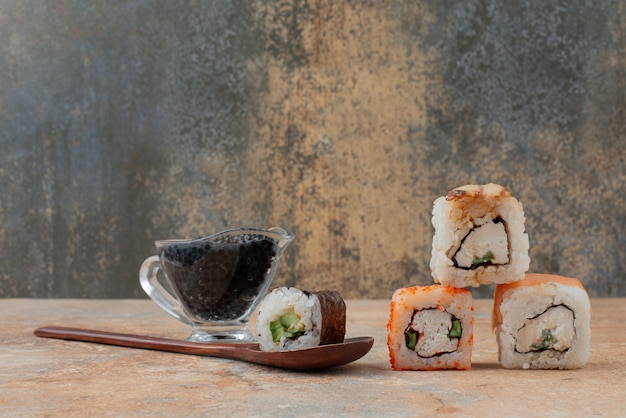 Ensemble de délicieux sushi roll avec cuillère et sauce soja sur une surface en marbre