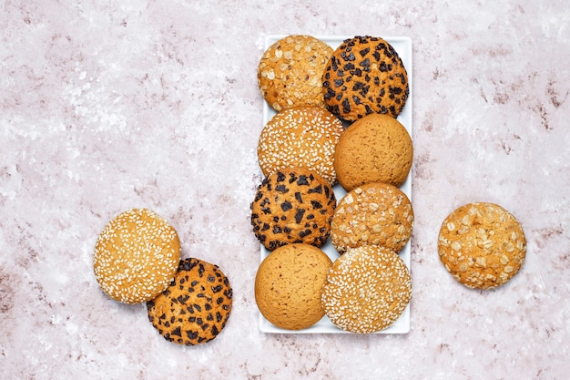 Ensemble de divers cookies de style américain sur un fond de béton clair. Sablés aux confettis, graines de sésame, beurre d'arachide, biscuits à l'avoine et aux pépites de chocolat.