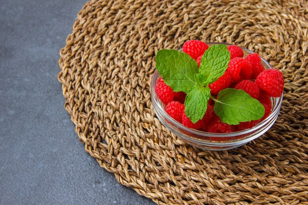 Ensemble de feuilles de menthe et de framboises dans une soucoupe sur un dessous de plat