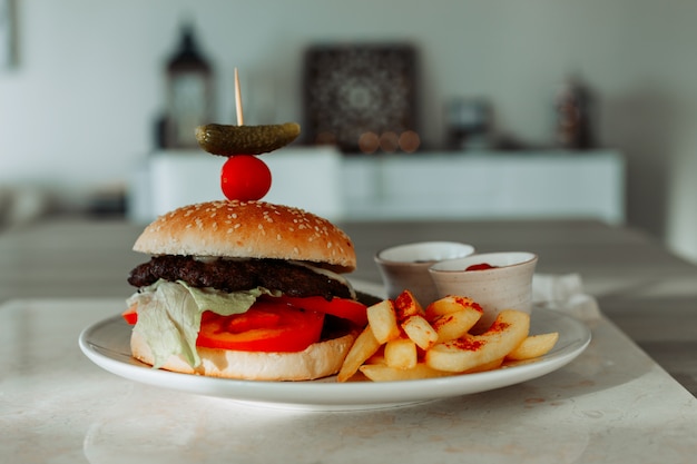 Ensemble de frites et hamburger dans une assiette avec cuisine et table.