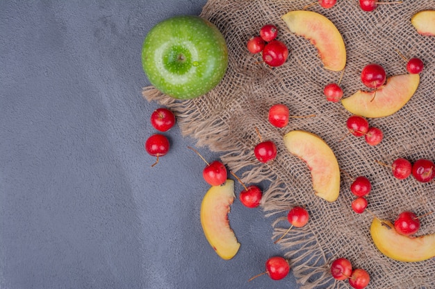 Ensemble de fruits. Pomme, cerises et tranches de pêche sur bleu.