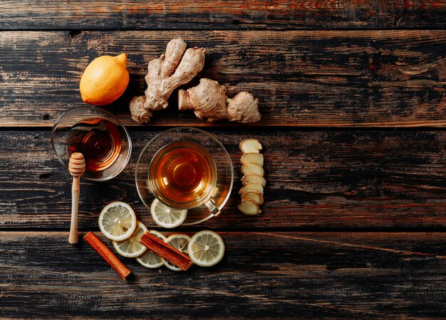 Ensemble de gingembre, miel, cannelle sèche, thé et vert et citron sur fond de bois foncé. vue de dessus. espace pour le texte