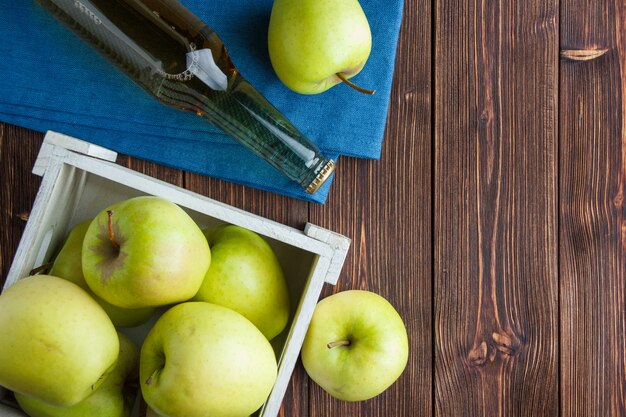 Ensemble de jus de pomme et de pommes vertes dans une boîte en bois sur un tissu et un fond en bois. mise à plat. espace pour le texte