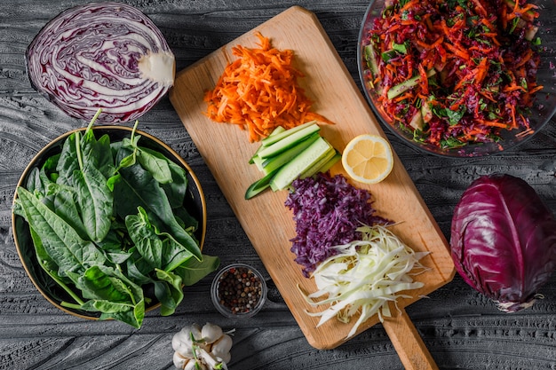 Ensemble de légumes verts et salade de légumes dans des bols sur un tissu de pique-nique et un fond en bois foncé. vue de dessus. espace pour le texte