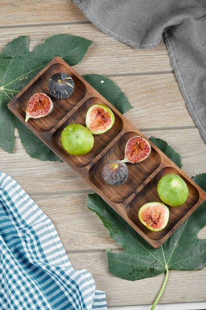 Ensemble Mûr Et Tranches De Figues Vertes Et Noires Sur Un Plateau En Bois Avec Une Feuille Et Une Nappe.