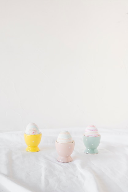 Ensemble d&#39;oeufs de Pâques dans des tasses sur textile léger