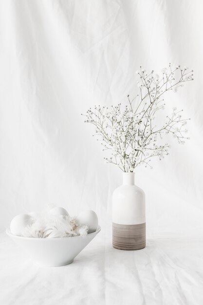 Ensemble d&#39;oeufs de Pâques et de piquants dans un bol près de branches de plantes dans un vase