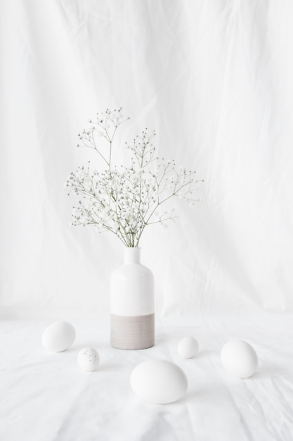 Ensemble d&#39;oeufs de Pâques près de branches de plantes dans un vase