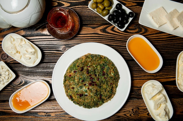 Ensemble de petit-déjeuner composé de fromages, de miel, de thé et d'un kyukyu traditionnel azéri