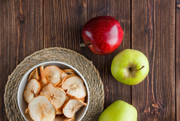 Ensemble de pomme fraîche et de pommes séchées dans un bol sur un tissu et un fond en bois. vue de dessus.