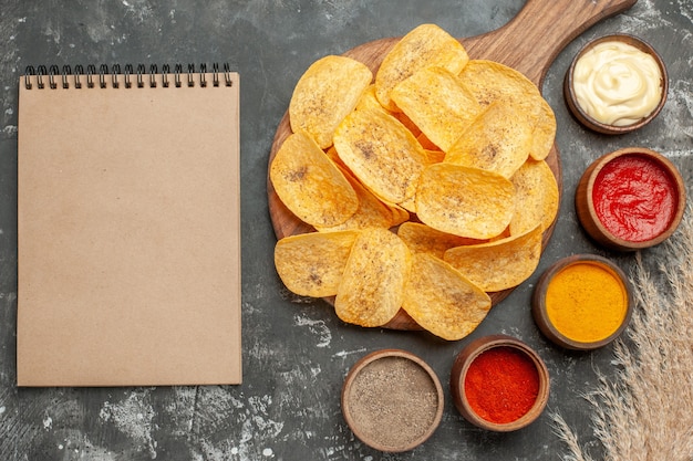 Ensemble pour les croustilles contenant différentes épices mayonnaise et ketchup sur tableau gris