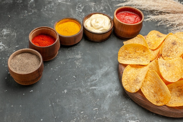 Ensemble pour les croustilles contenant différentes épices mayonnaise et ketchup sur tableau gris