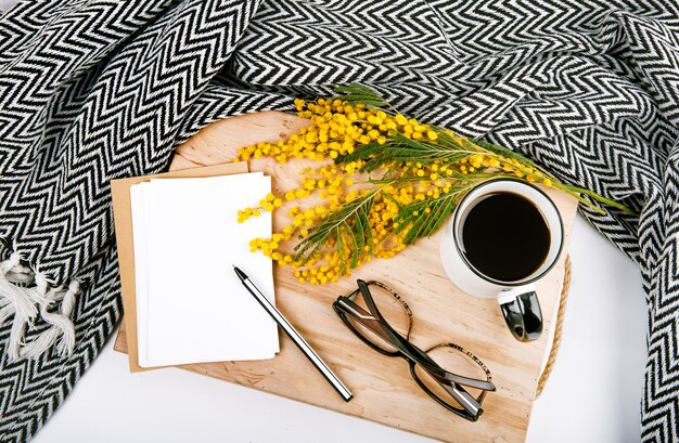 ensemble de printemps avec des fleurs jaune plaid mimosa tasse avec des cartes postales de café stylo lunettes