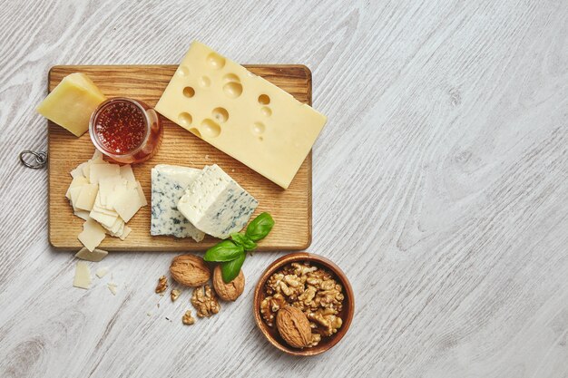 Ensemble de quatre fromages sur une planche à découper rustique isolé sur le côté de la table en bois blanc brossé