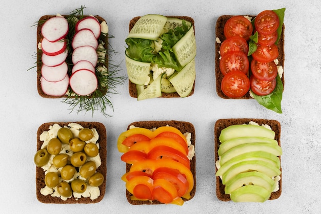 Ensemble de sandwichs à face ouverte sur fond de pierre blanche. sandwichs végétariens aux légumes au fromage, radis à l'aneth, olives, tomate au basilic,