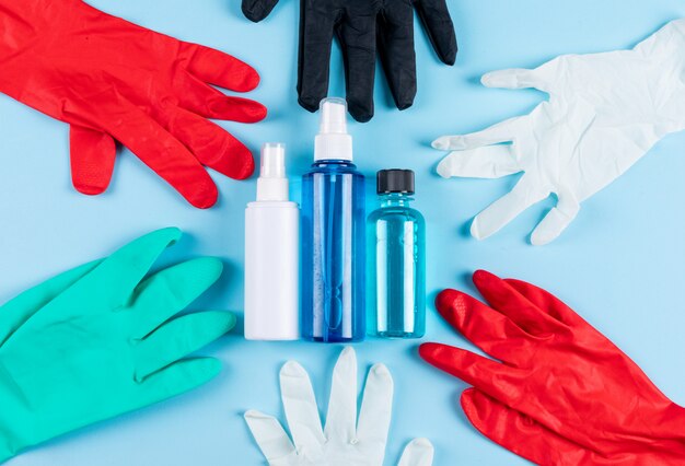 Ensemble de sprays, masque médical et gants médicaux sur fond cyan clair. vue de dessus.