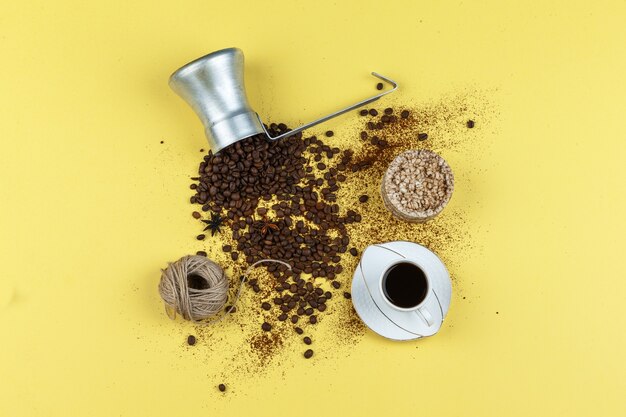 Ensemble de tasse de café, gâteaux de riz, cordes et grains de café dans une cruche sur fond jaune. pose à plat.