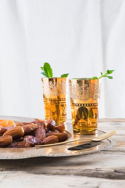 Ensemble de tasses avec des brindilles de plantes et de fruits secs près de la cuillère sur le plateau de la table