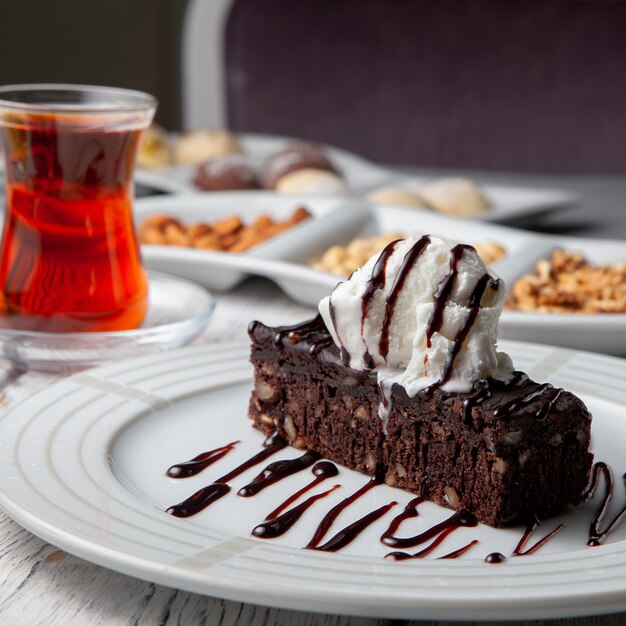 Ensemble de thé, noix et dessert dans une assiette sur un fond en bois blanc. vue de côté.