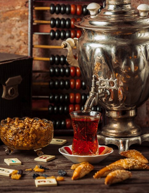 Ensemble de thé de samovar traditionnel avec une variété de collations, de bonbons et de fruits secs.