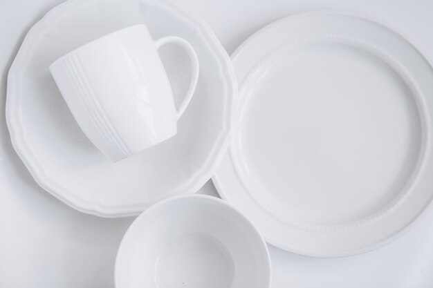 ensemble d&#39;ustensiles blancs de trois assiettes différentes et une tasse dans une assiette