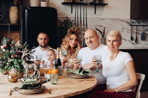 Enthousiaste belle famille caucasienne avec bébé célébrant le nouvel an à la table de cuisine en bois.