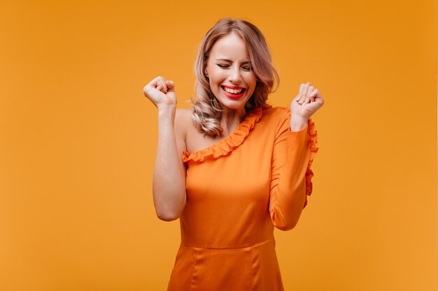 Enthousiaste belle femme en riant les yeux fermés sur le mur jaune