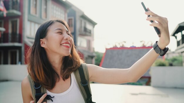 Enthousiaste belle jeune femme asiatique blogueur backpacker à l&#39;aide de smartphone prenant selfie