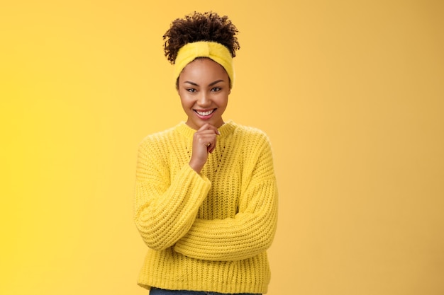 Enthousiaste créative belle jeune femme noire portant un bandeau de chandail excellent plan souriant satisfait ravi regarder caméra réfléchie maquillage idée, debout fond jaune.