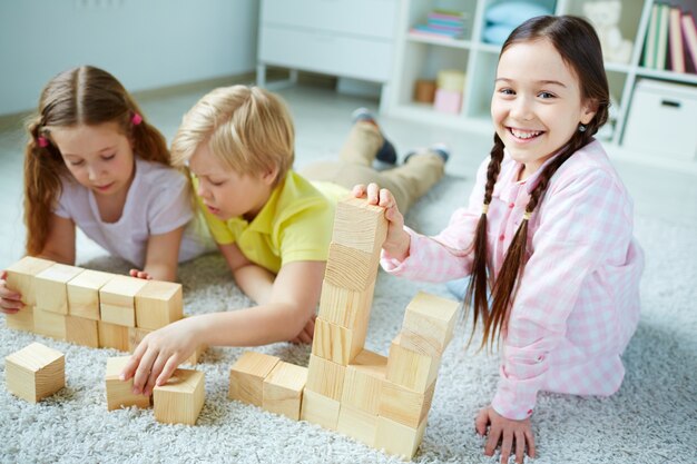 Enthousiaste écolière amusant avec des cubes en bois