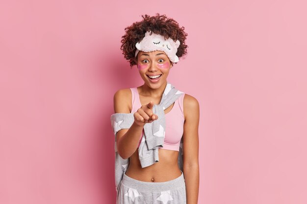 Enthousiaste femme afro-américaine aux cheveux bouclés indique l'index à vous montre quelque chose devant