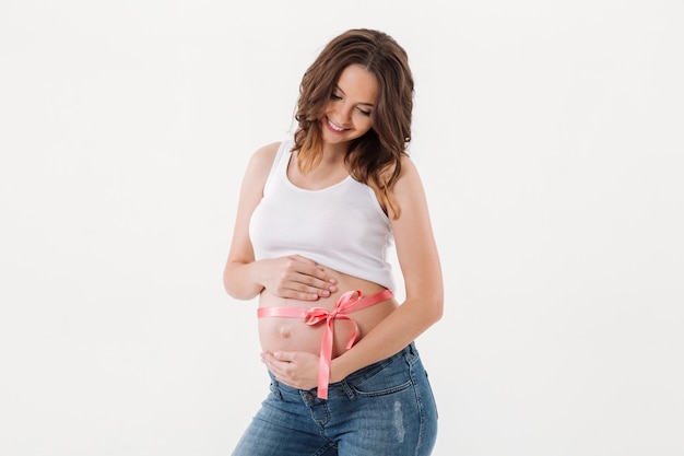 Enthousiaste femme enceinte debout isolé avec un arc sur le ventre