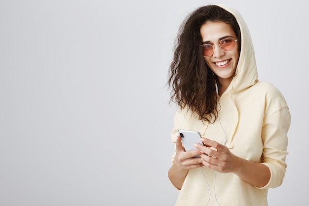 Enthousiaste femme souriante à l'aide de téléphone mobile