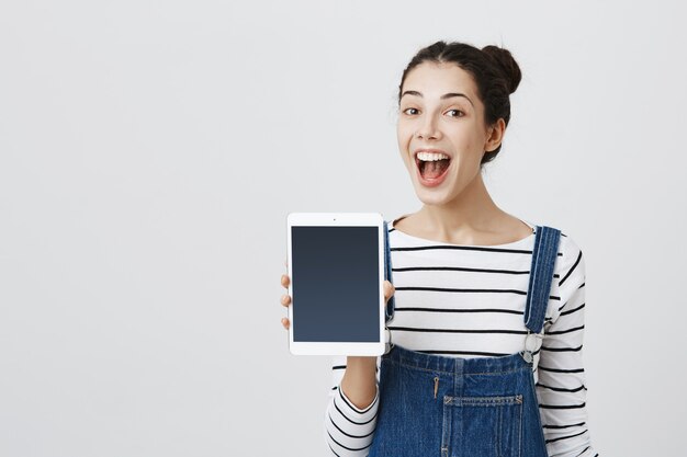 Enthousiaste femme souriante promouvoir l'application tablette numérique, afficher l'écran