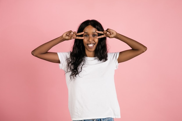 Photo gratuite enthousiaste jeune femme afro-américaine isolée sur l'espace corallien, émotionnelle et expressive