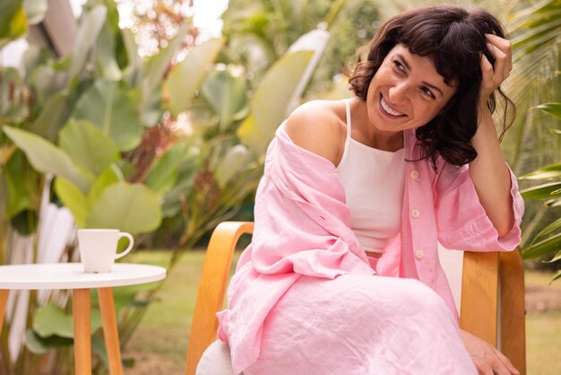 Enthousiaste jeune femme brune caucasienne profitant de vacances assis sur une chaise dans le jardin en été Concept de solitude avec la nature