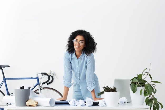 Photo gratuite enthousiaste jeune femme designer d'intérieur à la peau sombre portant des lunettes élégantes