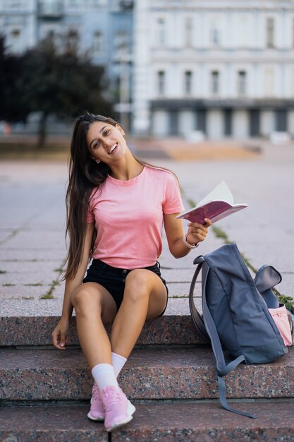 Enthousiaste jeune femme prenant des notes alors qu'il était assis sur les marches dans la rue