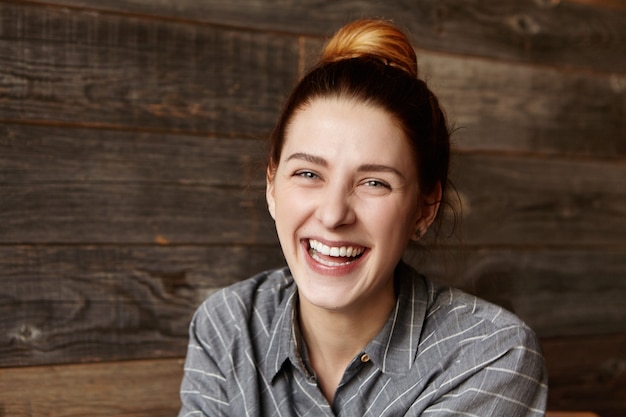 Photo gratuite enthousiaste jeune femme de race blanche portant ses cheveux rouges en chignon en riant aux éclats