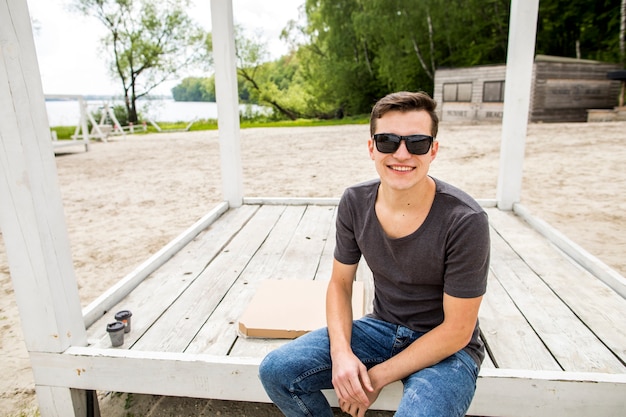 Enthousiaste jeune homme assis sur la plage