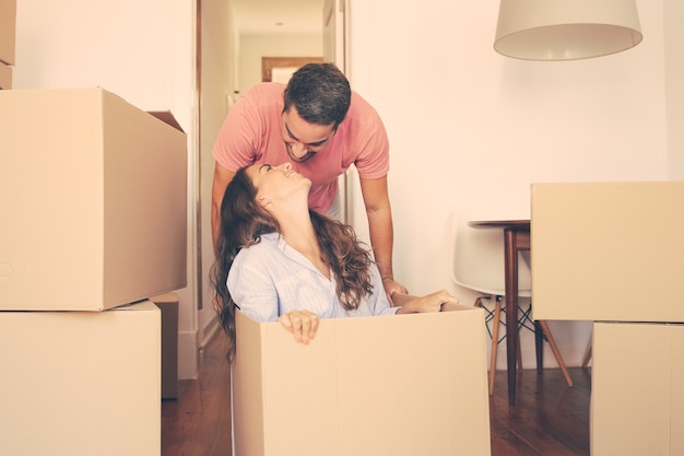 Enthousiaste jeune homme faisant glisser la boîte avec sa petite amie à l'intérieur et l'embrassant