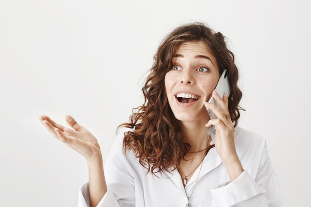 Enthousiaste jolie femme parlant au téléphone mobile excité, souriant