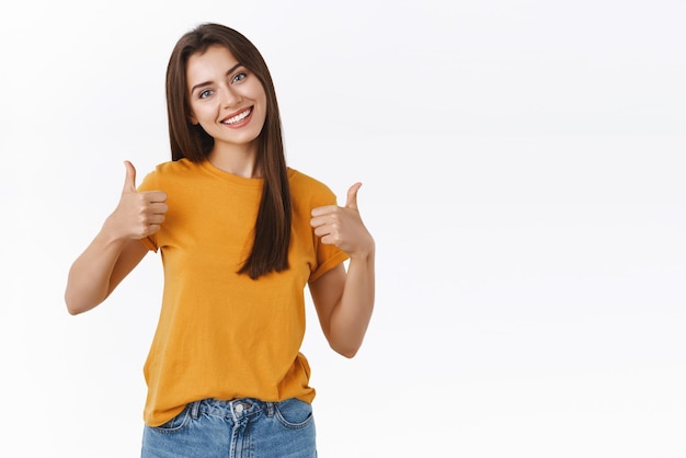 Enthousiaste jolie fille souriante se sentant heureuse et satisfaite recommander un bon café montrer la tête inclinée vers le haut et sourire en signe d'approbation laisser des commentaires positifs debout heureux sur fond blanc