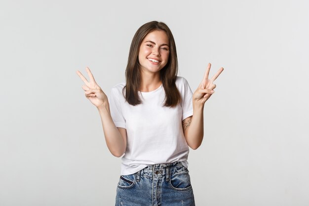 Enthousiaste jolie jeune femme souriante, montrant des gestes de paix.