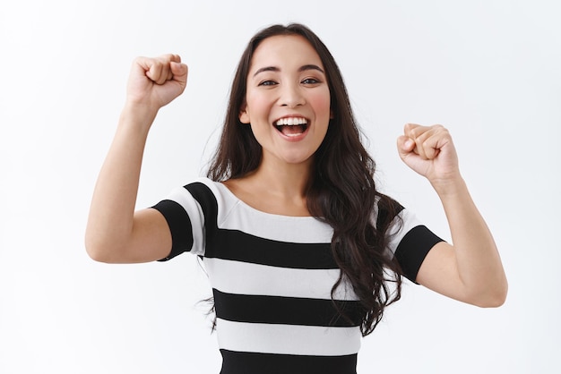 Enthousiaste et solidaire, une jeune petite amie heureuse encourage l'équipe à marquer le but de la pompe à poing et souriant en applaudissant ou enracinant pour un ami debout joyeux et diverti sur fond blanc