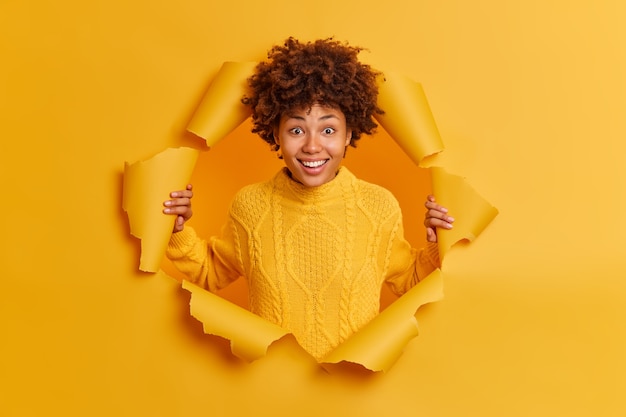 Photo gratuite enthousiaste souriante jeune femme afro-américaine à la peau sombre pose dans du papier déchiré