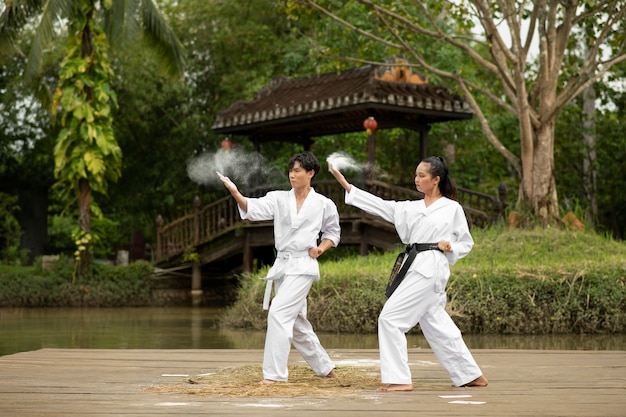 Photo gratuite entraînement de taekwondo se déroulant à l'extérieur dans la nature avec deux personnes