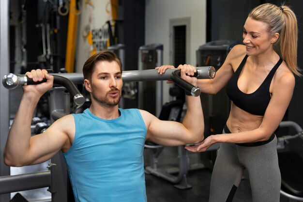 Photo gratuite entraîneur aidant le débutant au gymnase